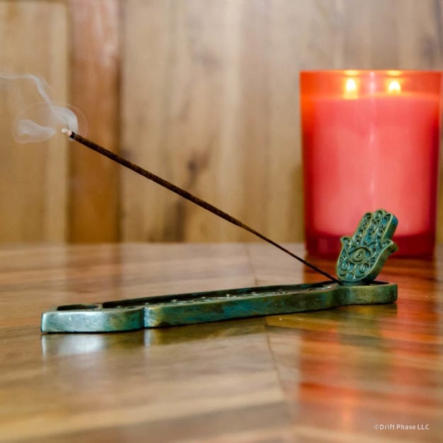 Green and bronze hamsa hand incense burner with burring incent.