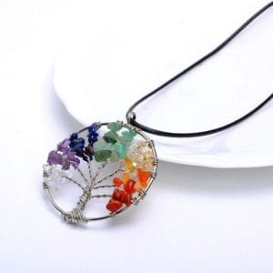 Photo of the 7 Chakra Natural Stone Pendant with cord laying against a jewelry dish.